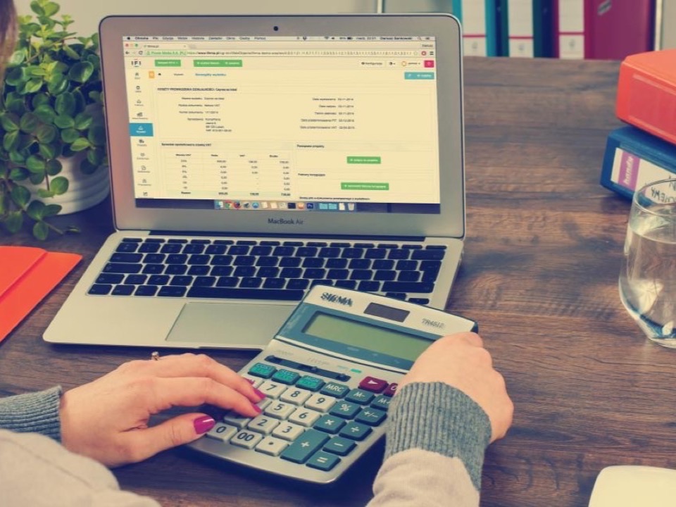 Un tableau de gestion ouvert sur un ordinateur portable, une calculatrice à côté
